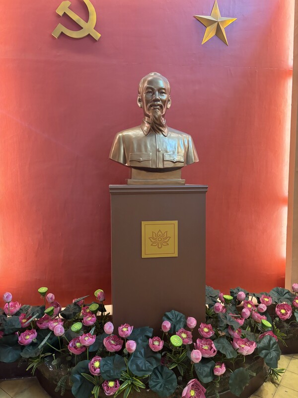 bronze bust Ho Chi Minh against a red background